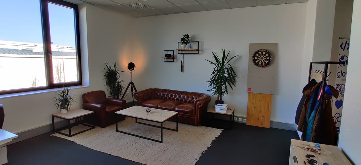 Common room in the Cloudflight office in Ried with a cozy couch, a table and a dartboard