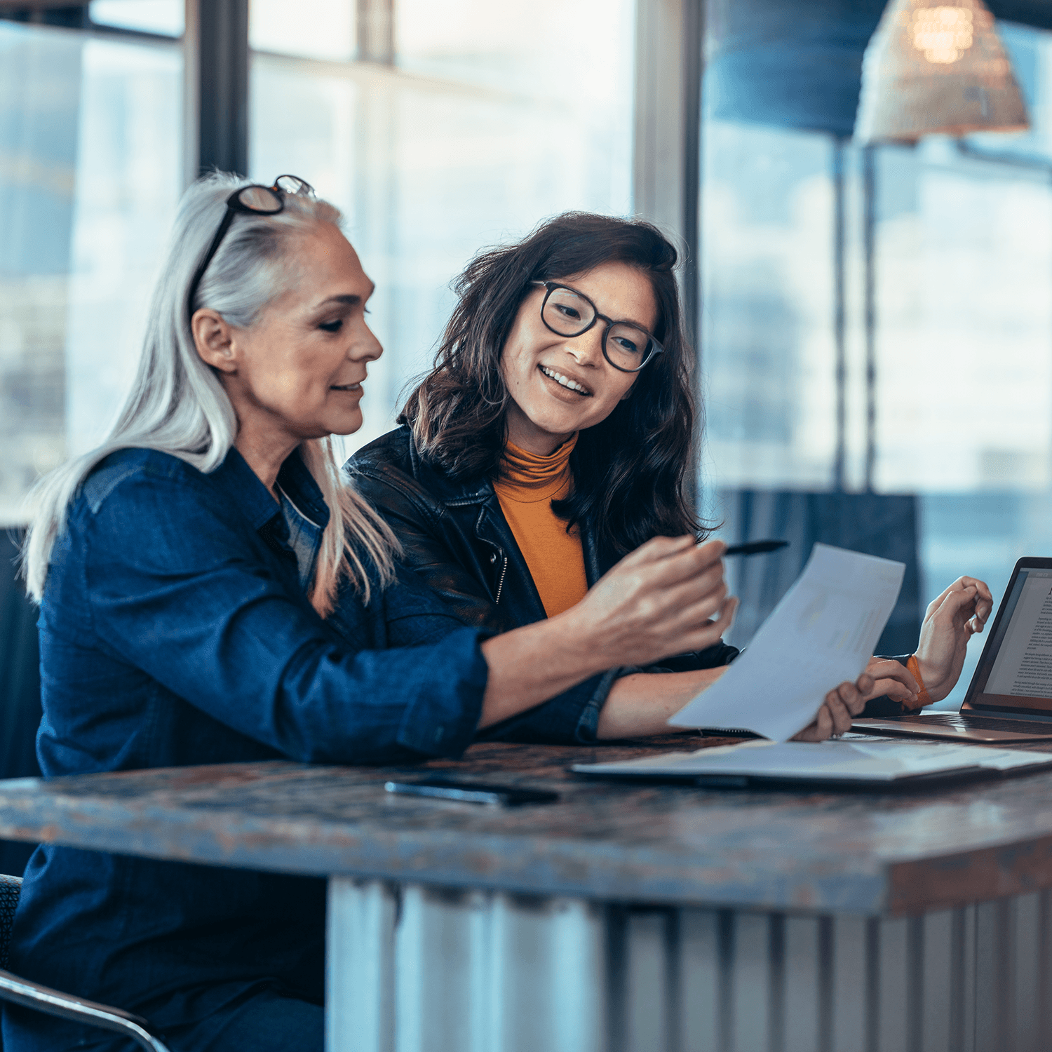 Woman executives at work in office discussing some paperwork.