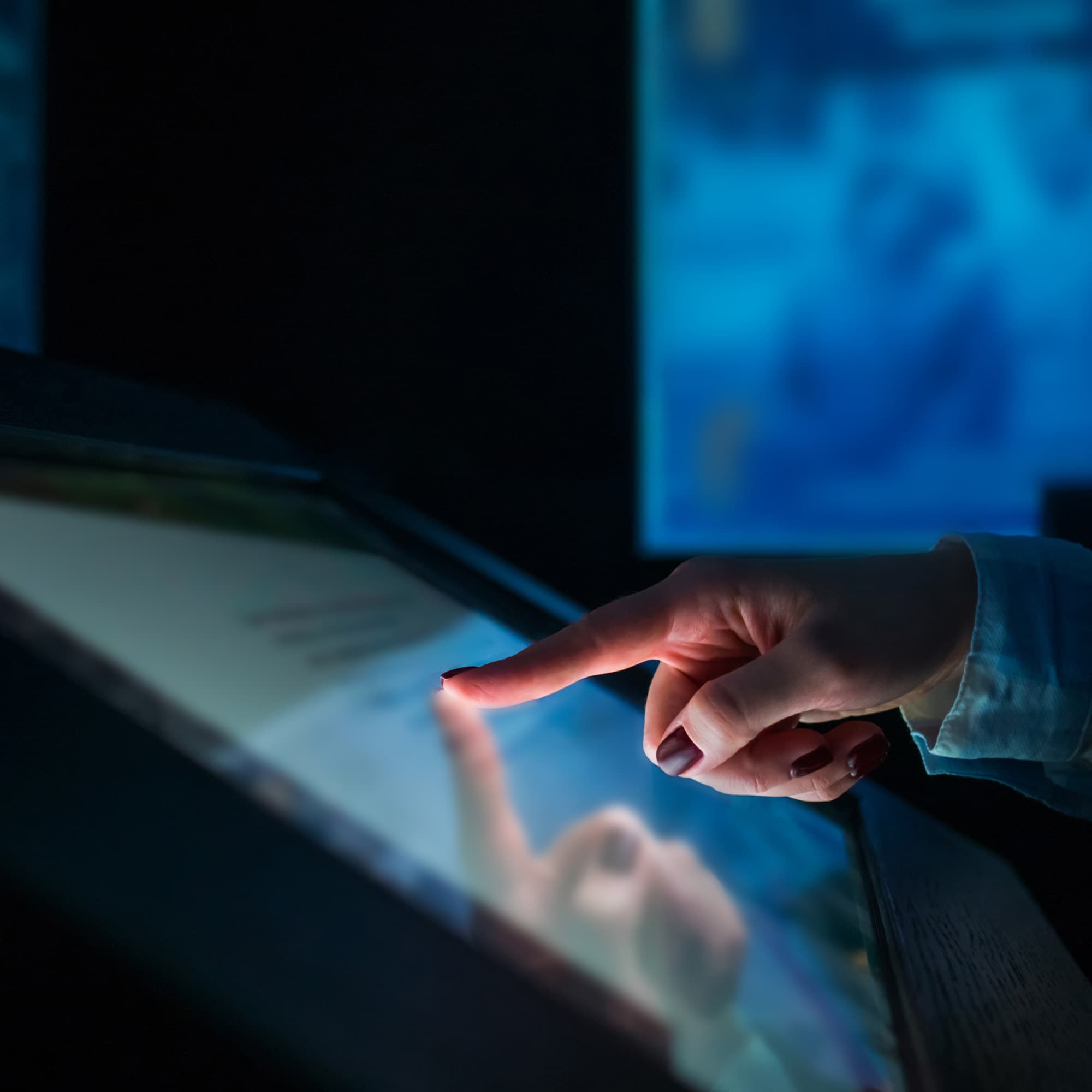 woman using interactive touchscreen display of electronic kiosk at modern museum or exhibition