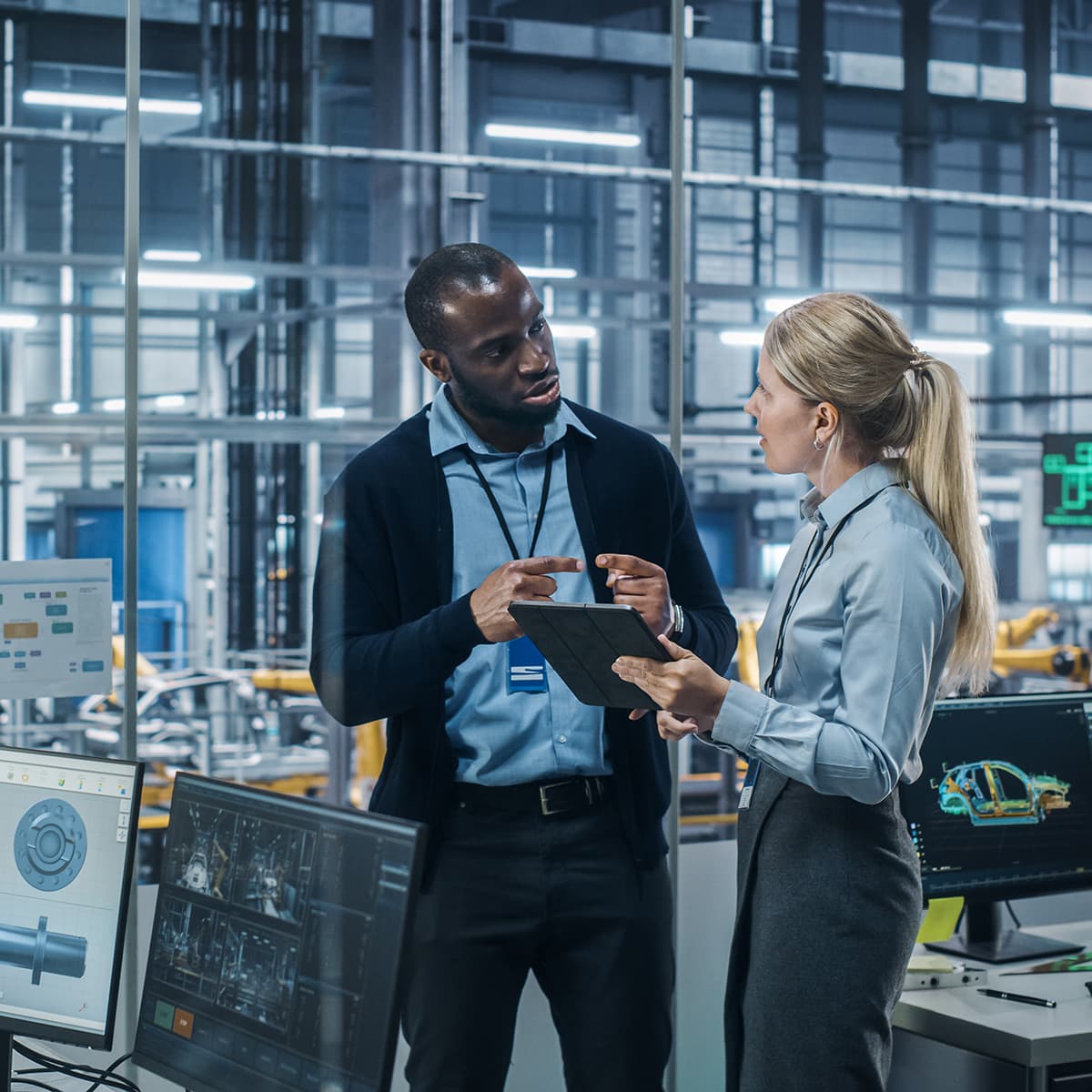 Car Factory Office: Female Engineer Talks with Male Scientist, Use Tablet Computer to Design Production Conveyor for Advanced Power Engines