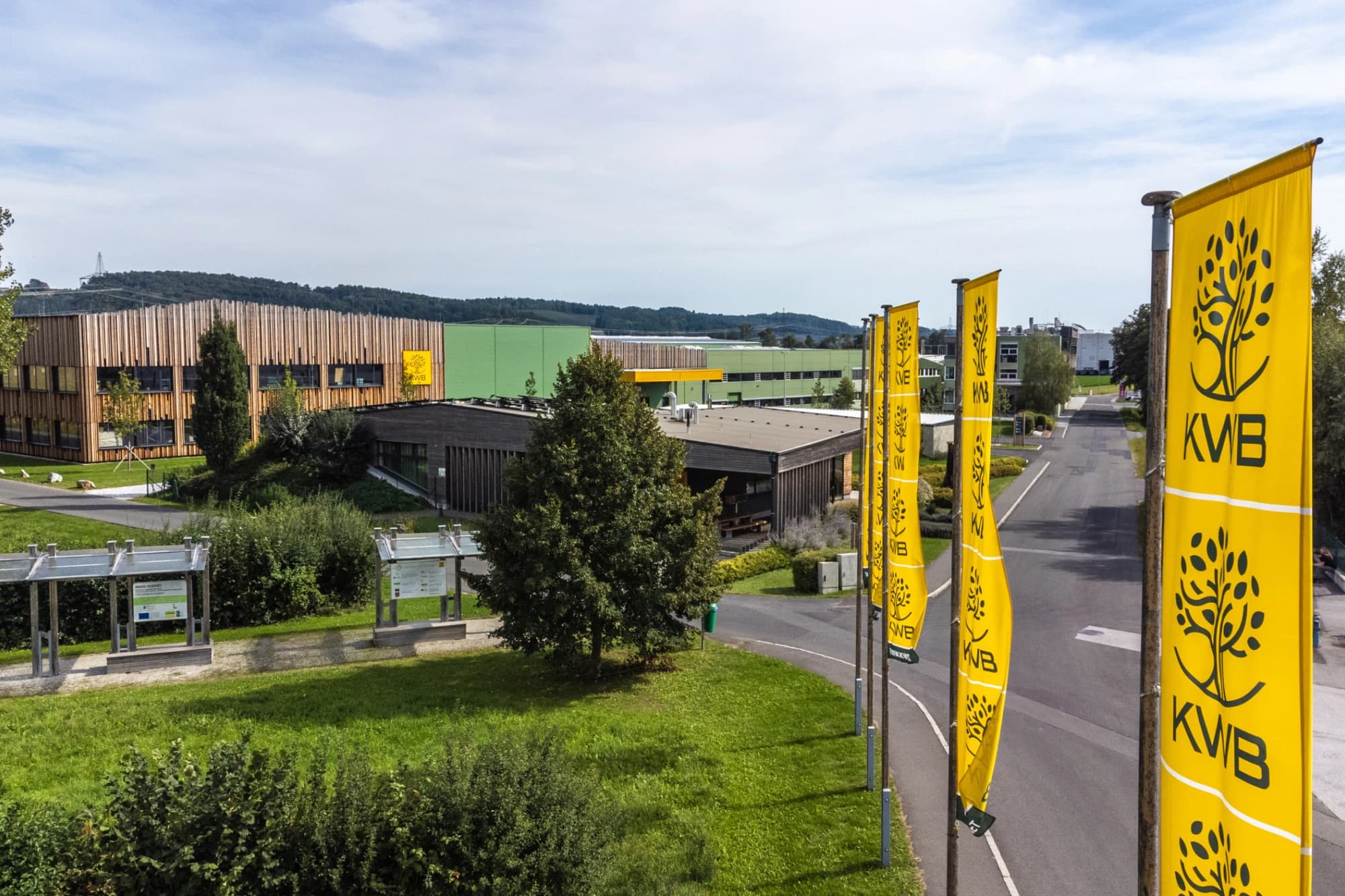 An aerial view of a modern office building complex, with yellow KWB flags lining a road in the foreground of the Austria’s Parliament Mein Parlament site.